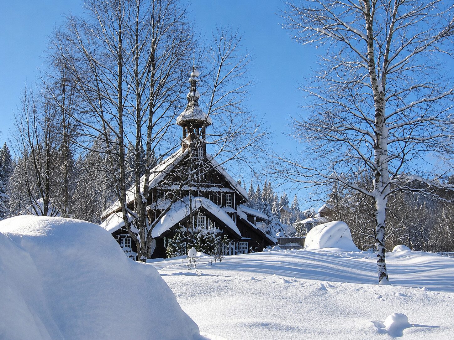 Die neue Tussetkapelle im Winter, tief eingeschneit, vor blauem Himmel
